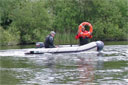 picture of boat approaching test area the steward is holding retrieve object (life ring) above head waiting for signal to drop it.