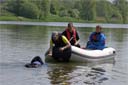 picture of black newfoundland dog arriving at boat, carrying a rope. The boat steward is leaning out to collect the rope