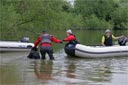picture of owner holding black newfoundland dog, he has reached out and taken hold of the boat stewards hand indicating that the boat is within reach of the owner